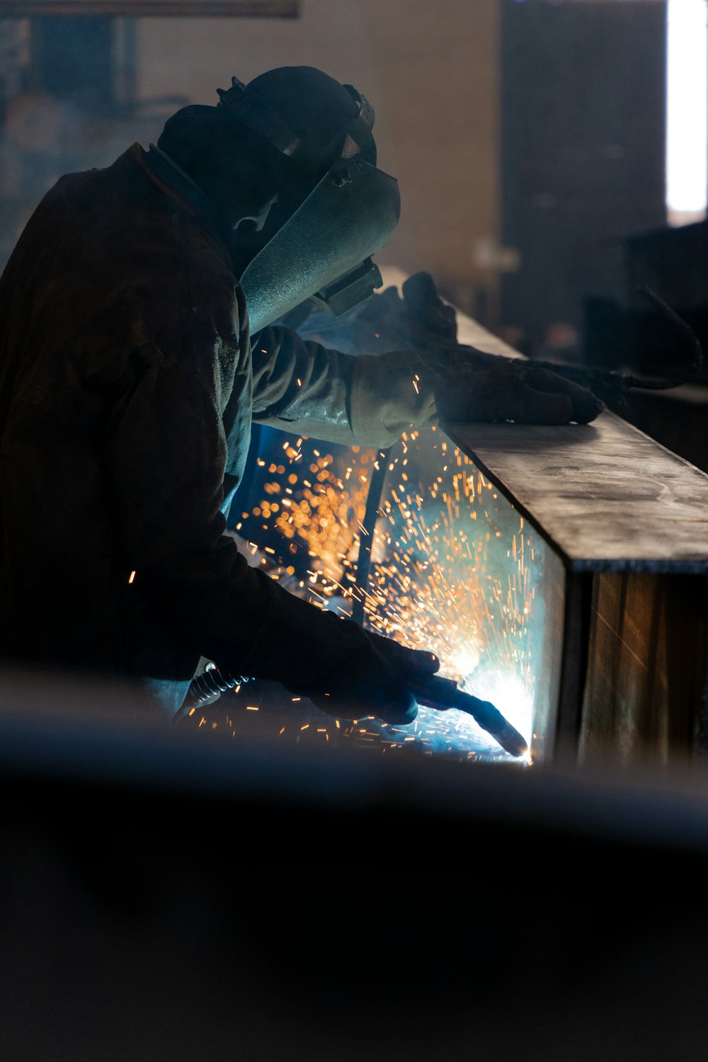 Welder laying a precision bead, sparks flying in the shop